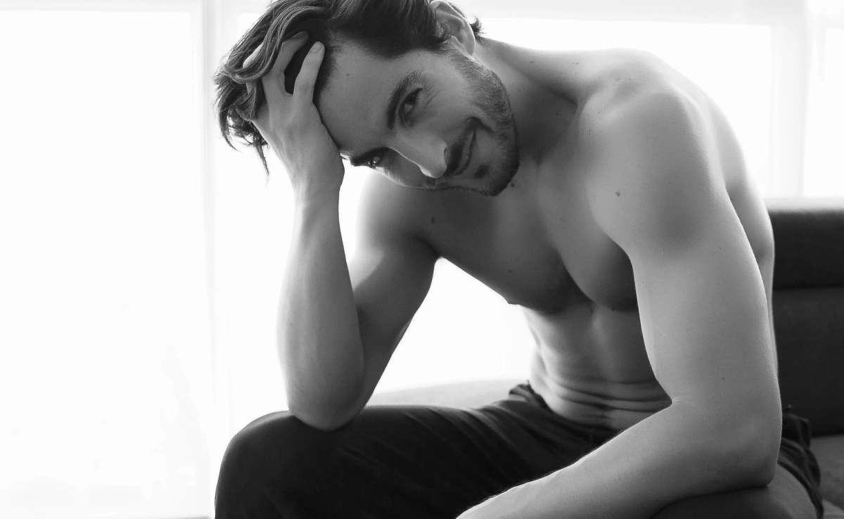 Portrait of Young Shirtless White Man With Beautiful Hair is smiling and looking at the camera. Athletic and Muscular Caucasian Male With fingers Through His Hair Looking Confident